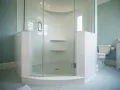 Salle de bain avec carrelage bleu pâle et une douche d'angle. Ce receveur de douche à éviter, avec ses étagères peu pratiques, est un cauchemar à nettoyer.