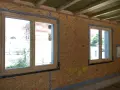 Okna na budowie, gotowe do montażu. Widać izolację i płyty OSB. Czym zabić okna na budowie? Tutaj jeszcze nie są zamontowane.