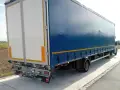 Tylna część niebieskiej naczepy z białymi drzwiami, stojąca na poboczu. To część zespołu pojazdów gotowego do drogi.