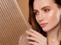 Kobieta z idealną cerą, która emanuje blaskiem, niczym efekt glass skin. Delikatne linie na pierwszym planie dodają głębi.