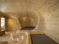 Interior de una casa cueva con paredes y techo de madera curvada, creando un espacio orgánico y acogedor.