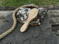 Cucchiaio grezzo in legno d'acero, appoggiato su un tronco scuro con una corda rustica.
