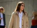 Donna sorridente con capelli lunghi e castani indossa un trench beige aperto su una camicia a righe azzurre. Perfetto per ogni occasione, anche se posso mettere il trench di sera.