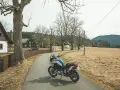 Motocykl czeka na jednodniowy wypad motocyklowy. W tle wiejskie domki i puste pola.