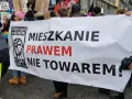 Protestujący niosą transparent "Mieszkanie prawem nie towarem!", domagając się ustaw chroniących lokatorów.