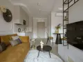 Nowoczesny salon z kanapą w kolorze musztardowym, tworzącą ciepłą paletę kolorów ziemi.