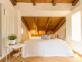 Accogliente camera da letto in mansarda con travi a vista in legno. Idee per un nido romantico e funzionale.
