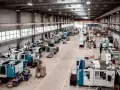 Hala produkcyjna z maszynami, gdzie trwa szybkie prototypowanie. Widać linie produkcyjne, magazyny i pracowników.