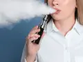 Mujer exhala vapor de un vaper, una alternativa moderna al tabaco tradicional.
