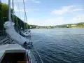 Segelbåtar vid kaj i Lilla Edet, en bro syns i bakgrunden över en bred flod.