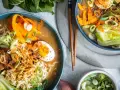 Zwei Schüsseln dampfendes Miso Ramen mit Nudeln, Ei, Karotten, Pak Choi und Frühlingszwiebeln.