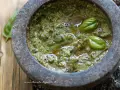 Pesto genovese originale appena preparato nel mortaio, con basilico fresco e olio d'oliva.