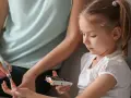 Mutter hilft Kind bei Blutzuckermessung. Ein wichtiger Teil im Leben mit diabetes kinder.