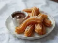 Churros przepis: złociste, chrupiące paluszki posypane cukrem, podane z miseczką gorącej czekolady. Idealne na deser!