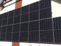 Duży zestaw paneli fotowoltaicznych na pionowej ścianie domu, zbierający energię słoneczną.