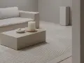 Salon w odcieniach ivory: sofa, stolik kawowy, świeca i dywan z geometrycznym wzorem tworzą spokojną aranżację.