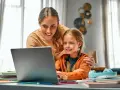 Mama pomaga córce w nauce online. Dni opieki na dziecko mogą być pełne wspólnych chwil przy komputerze.