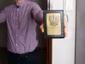 Mężczyzna w kratę pokazuje legitymację komornika. Zastanawiasz się, ile może zabrać komornik?