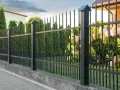 Betonowy murek jako alternatywa dla podmurówki pod ogrodzenie. Czarny metalowy płot z ostrymi zakończeniami.