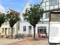 Blick auf die mittelalterliche Itzehoe Altstadt mit Fachwerkhäusern und einem Smartphone, das Informationen über die Stadt anzeigt.