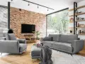 Nowoczesne, szare komplety wypoczynkowe z funkcją spania Black Red White. Wygodna sofa i fotel przy ceglanej ścianie.