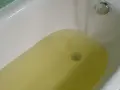 Wanna z żółtą wodą, z kranu leje się woda.