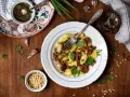Szybkie danie z gnocchi z grzybami i pesto, posypane orzeszkami pinii. Idealne na szybki obiad.
