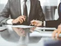Biznesmeni przy stole analizują dokumenty. Kto to syndyk? Prawdopodobnie jeden z nich, zajmujący się restrukturyzacją.
