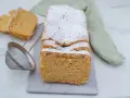 Puszysty makaron z mąki migdałowej, oprószony cukrem pudrem, czeka na spróbowanie. Obok leżą dwa kawałki ciasta i sitko.