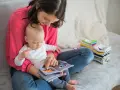 Mama czyta dziecku książeczkę o samochodach. Wycofane dziecko, przyczyny jego nieśmiałości mogą być różne, ale wspólne czytanie buduje więź.