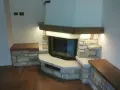 Un camino rustico in pietra e legno, con panche integrate. Un esempio di come costruire un camino rustico che unisce funzionalità ed estetica.