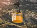 A yellow cable car ascends the rugged slopes of Montserrat.