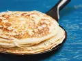 Stos puszystych naleśników na patelni, idealnych do wypróbowania nowego przepisu. Złociste i rumiane, kuszą swoim wyglądem.
