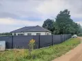 Ciemnoszara siatka na ogrodzeniu panelowym, idealna jako czym zasłonić ogrodzenie panelowe. Dom i samochód w tle.