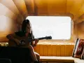Sarah Jones, piosenkarka, gra na gitarze w przytulnym wnętrzu.