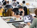 Des étudiants concentrés dans une école d'art, certains peignent, d'autres travaillent sur ordinateur. L'ambiance est studieuse.
