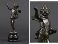 Brązowy putto z uskrzydlonymi plecami, w pozie gestykulacji, na ciemnym tle.