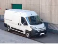 Biały bus dostawczy Fiat Ducato zaparkowany przy betonowej ścianie budynku.