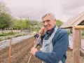 Uśmiechnięty starszy pan z łopatą w ręku, pracujący w ogrodzie. Zastanawia się, jaka emerytura z KRUS po 10 latach będzie mu przysługiwać.