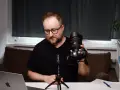 Mężczyzna prezentuje aparat fotograficzny, omawiając elementy kursu fotografii dla początkujących.