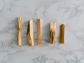 Seis trozos de palo santo sobre mármol. El palo santo se usa para purificar y aromatizar.