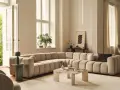 Ampio divano componibile color crema, dalle forme morbide e arrotondate, perfetto per definire le dimensioni di un salotto moderno.