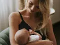 Uśmiechnięta mama karmi piersią swoje dziecko. Delikatne chwile bliskości i miłości.