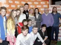 Rodzinka.pl obsada: młodzi aktorzy i starsze pokolenie pozują do wspólnego zdjęcia na tle ścianki z logo serialu.