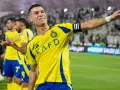 Uśmiechnięty Cristiano Ronaldo w żółtej koszulce Al Nassr, świętujący sukces. Jego zarobki w Arabii Saudyjskiej budzą podziw.