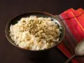 Un tazón de arroz de coco con semillas de calabaza y coco rallado, servido sobre una servilleta colorida.