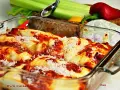 Pyszne, zapiekane cannelloni w sosie pomidorowym, posypane parmezanem. Obok świeże warzywa, idealne do dania.