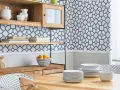Cocinas con papel pintado azul y blanco, estanterías de madera, vajilla y una mesa de comedor.