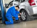 Meccanico in tuta blu lavora su una ruota, forse per montare gomme nuove davanti o dietro.