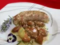 Une andouillette sauce moutarde, accompagnée de pommes de terre grenaille et garnie de romarin et d'une pensée.